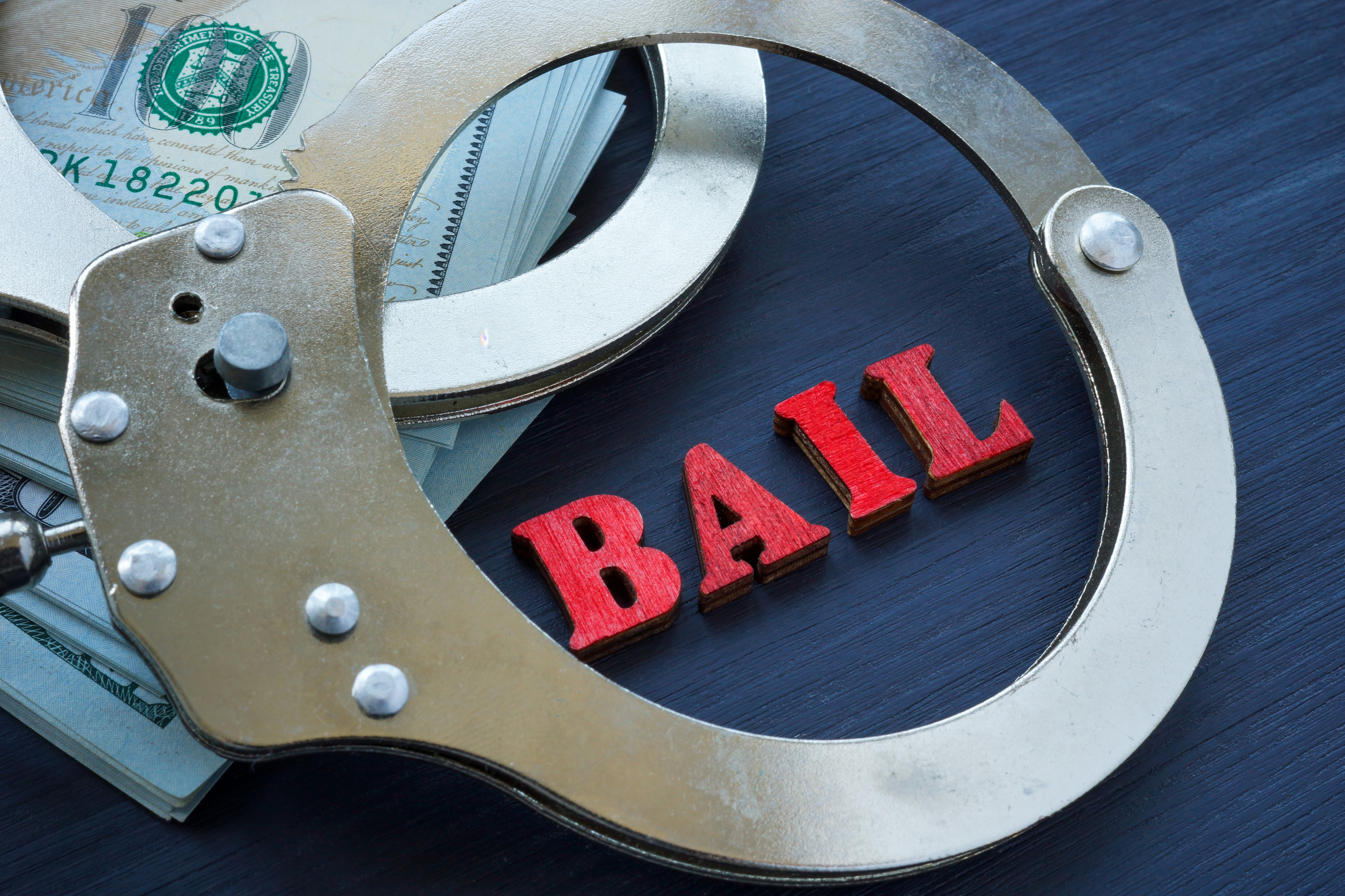 handcuffs and cash on a table with the word bail