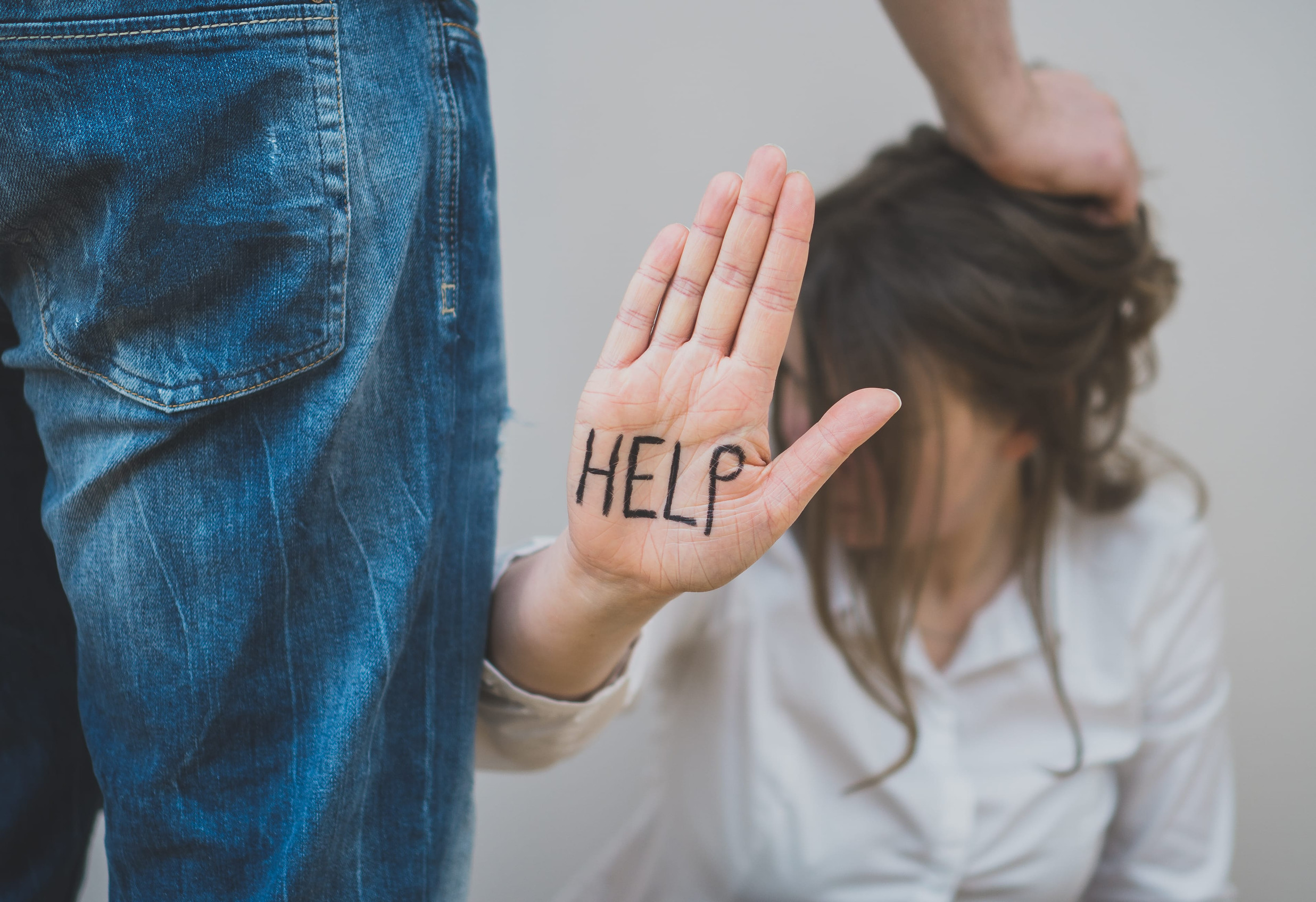 Domestic violence concept. Man pulling female's hair with the words help written on her palm